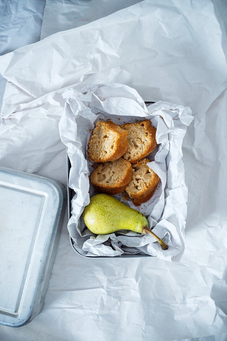 Brotdose mit Birne und vier Stücken veganem Birnengugelhupf aus Dinkel- und Maismehl, gesüßt mit Kokosblütenzucker