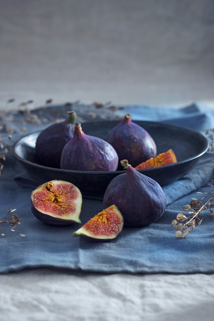 A bowl with four whole figs and one sliced fig