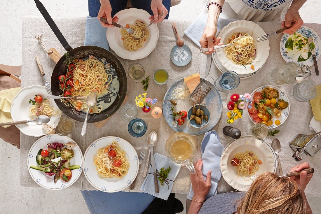 A set table with spaghetti, tomatoes and parmesan