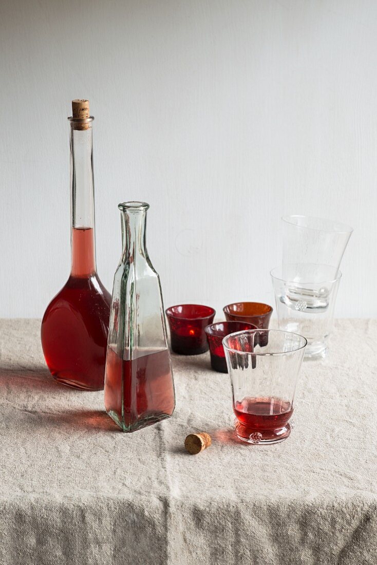 Rosewein in Flaschen und Gläsern auf beigem Tischtuch