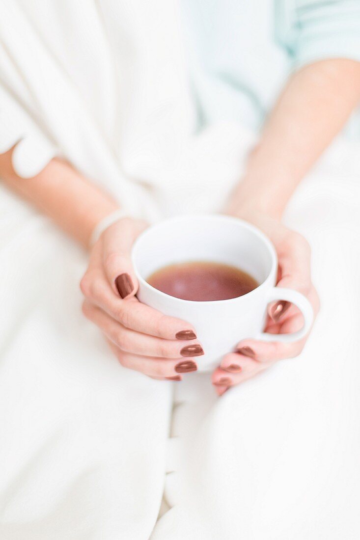 A woman's hands holding a cup of tea