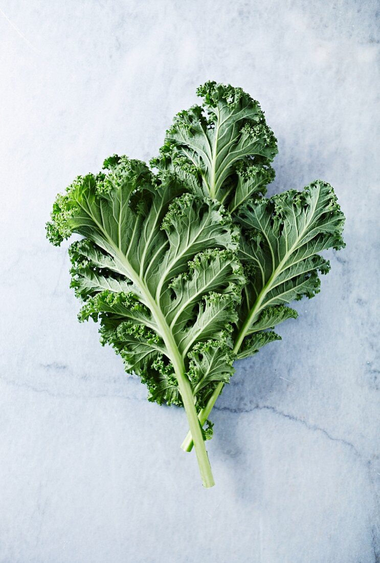 Fresh organic kale leaves on a marble background