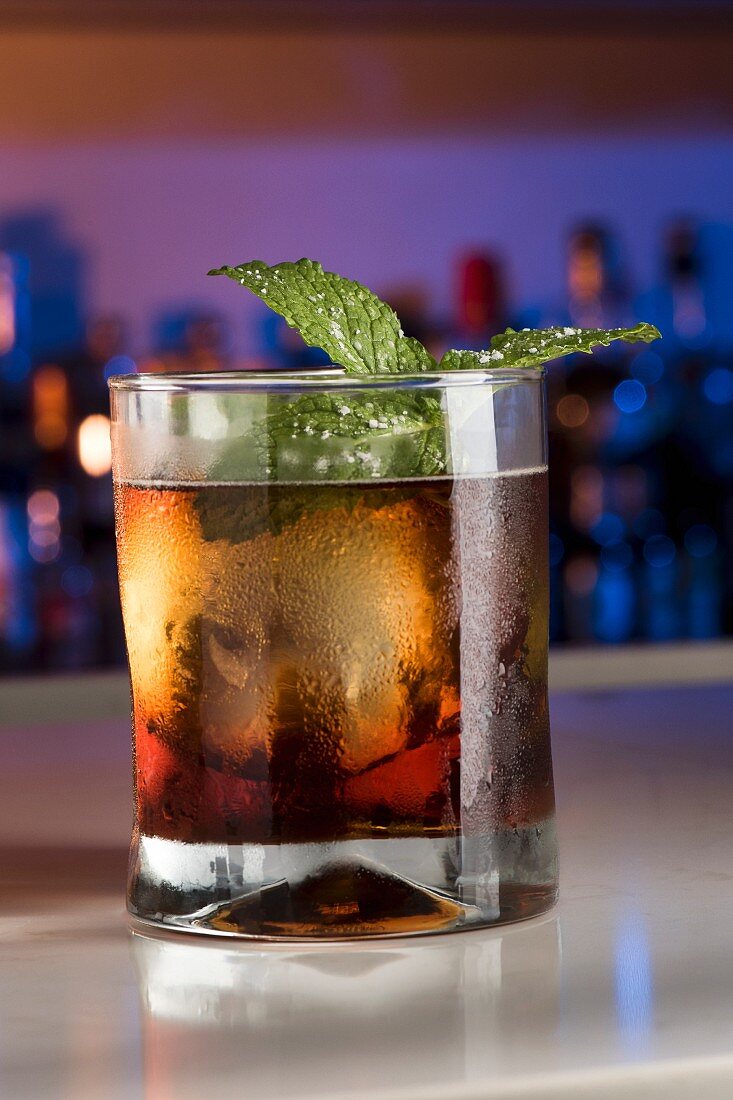 Aged rum cocktail with amaro, mint and ice cubes