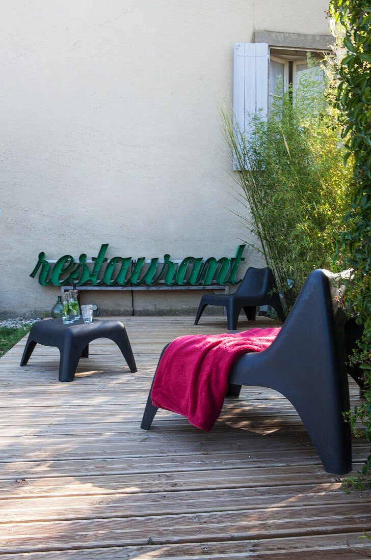 Retro neon sign and modern outdoor furniture on wooden terrace