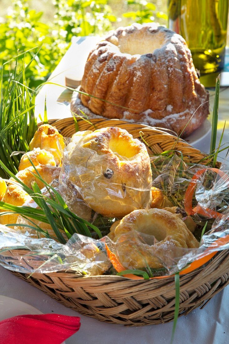 Bundt cakes of various sizes in basket on table in summery meadow