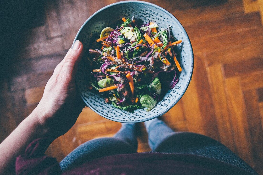 A woman holding a bowl of red cabbage salad