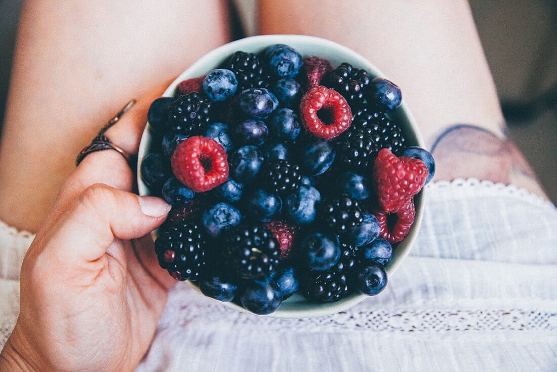 A woman holding a bowl of fresh berries