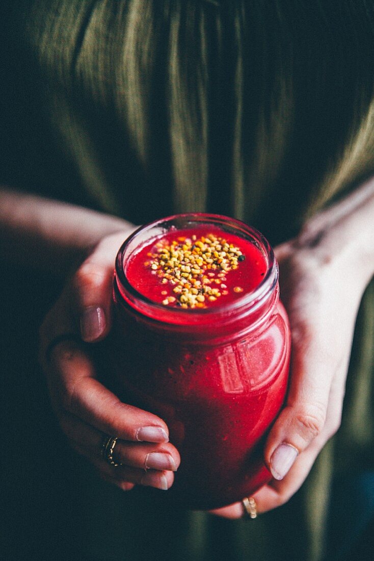 A woman holding a glass of raspberry smoothie