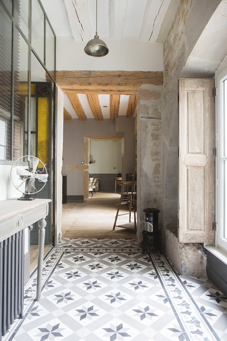 Cement-tiled floor, exposed masonry, shutters and console table in vintage-style hallway