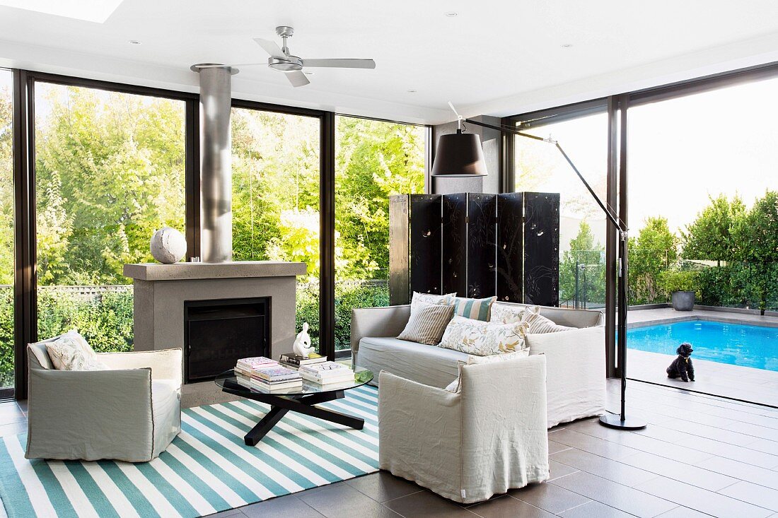 Summery living room with window front to the garden with pool