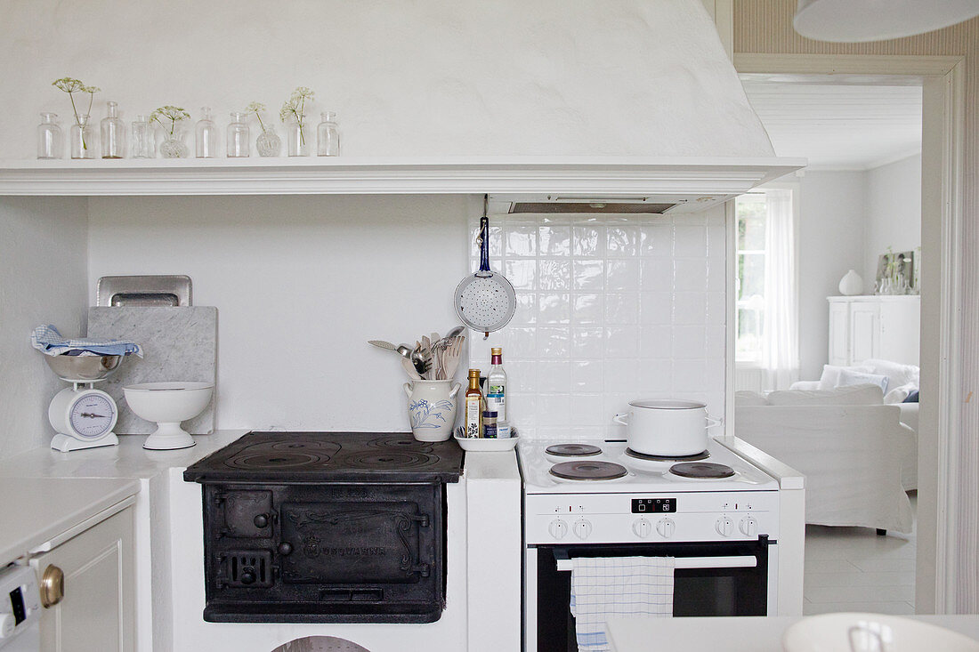 Old wood-fired stove and electric cooker below mantel hood