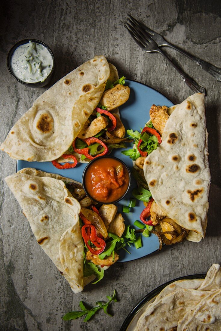 Tortilla wraps with spiced chicken, onion, peppers, salsa and a side serving of yoghurt dip