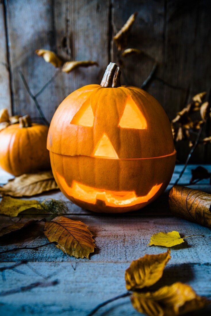 Halloween carved pumkin lantern with autumnal leaves