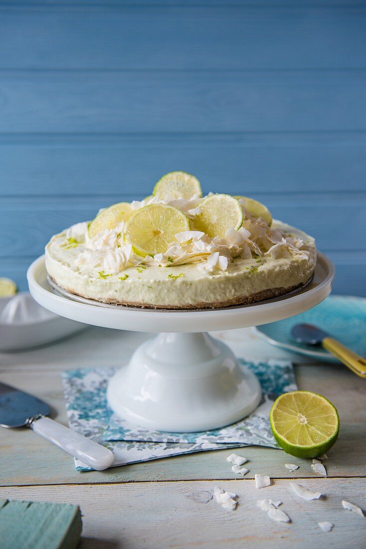 Lime and coconut cheesecake on a cake stand decorated with fresh lime slices