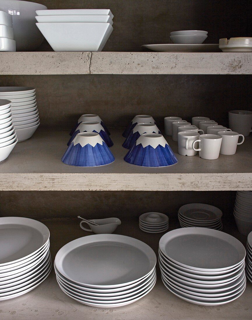 White crockery and blue-patterned cups on concrete shelves