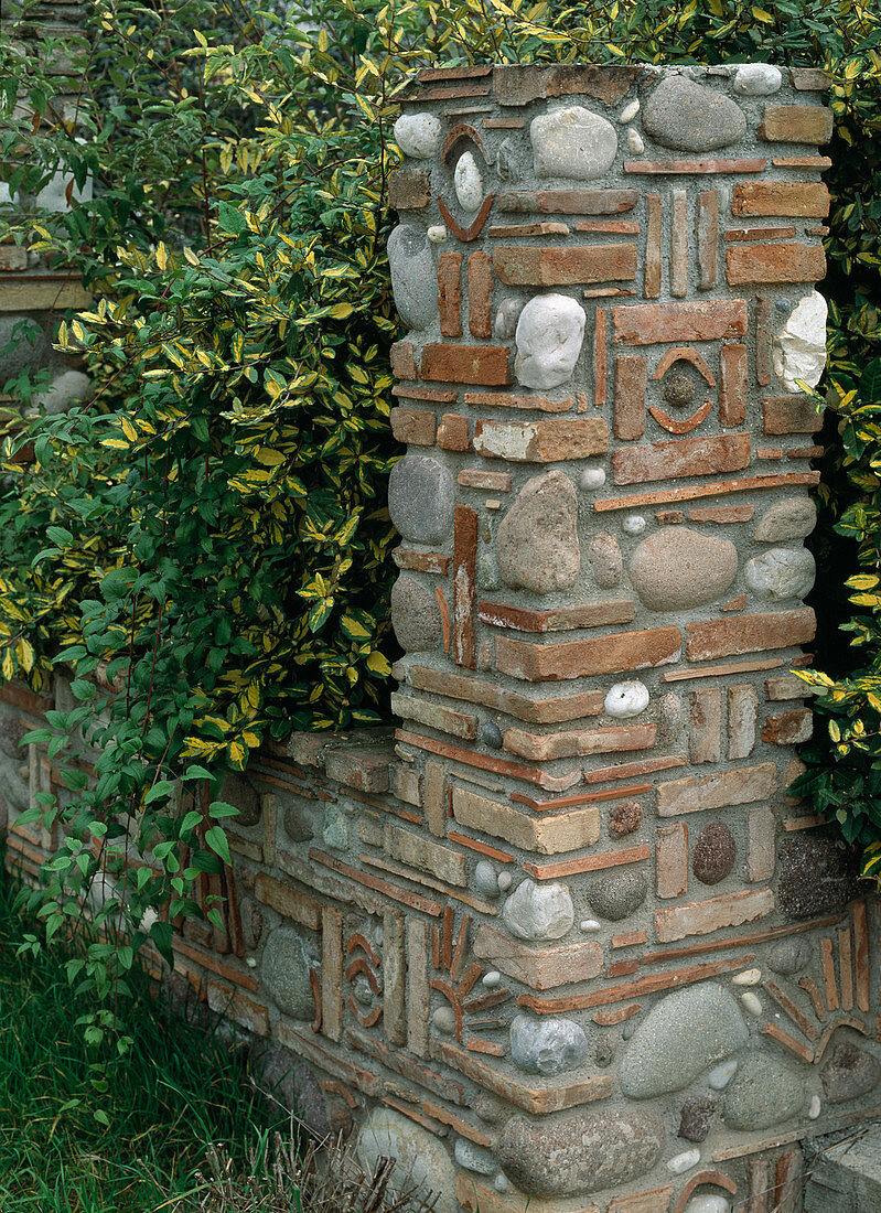 Kustvoll gestaltete Steinmauer und Pfosten aus Kieselsteinen