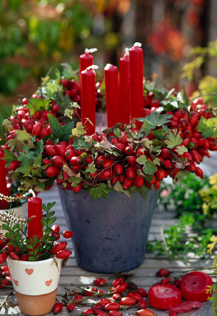 Candle decoration with wreath of pink (rosehips) and hedera (ivy)