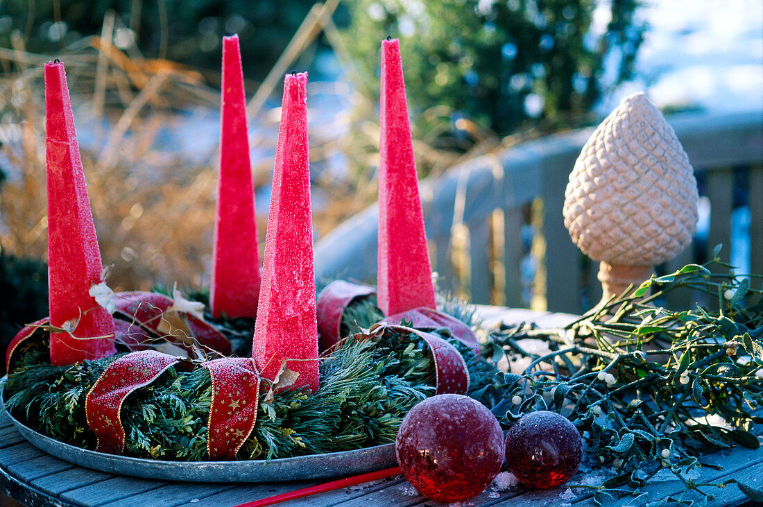 Advent wreath made of twigs with red pyramid candles and hoarfrost