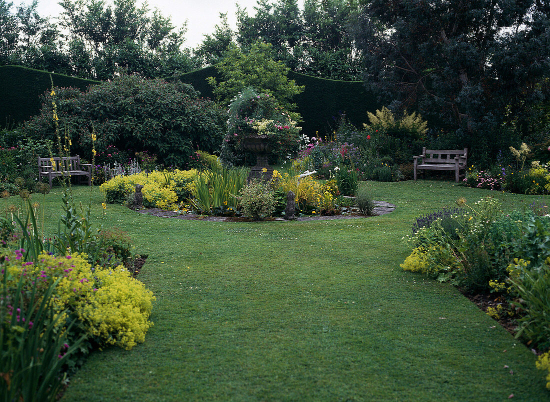 Summer garden with round central border with pond and perennials