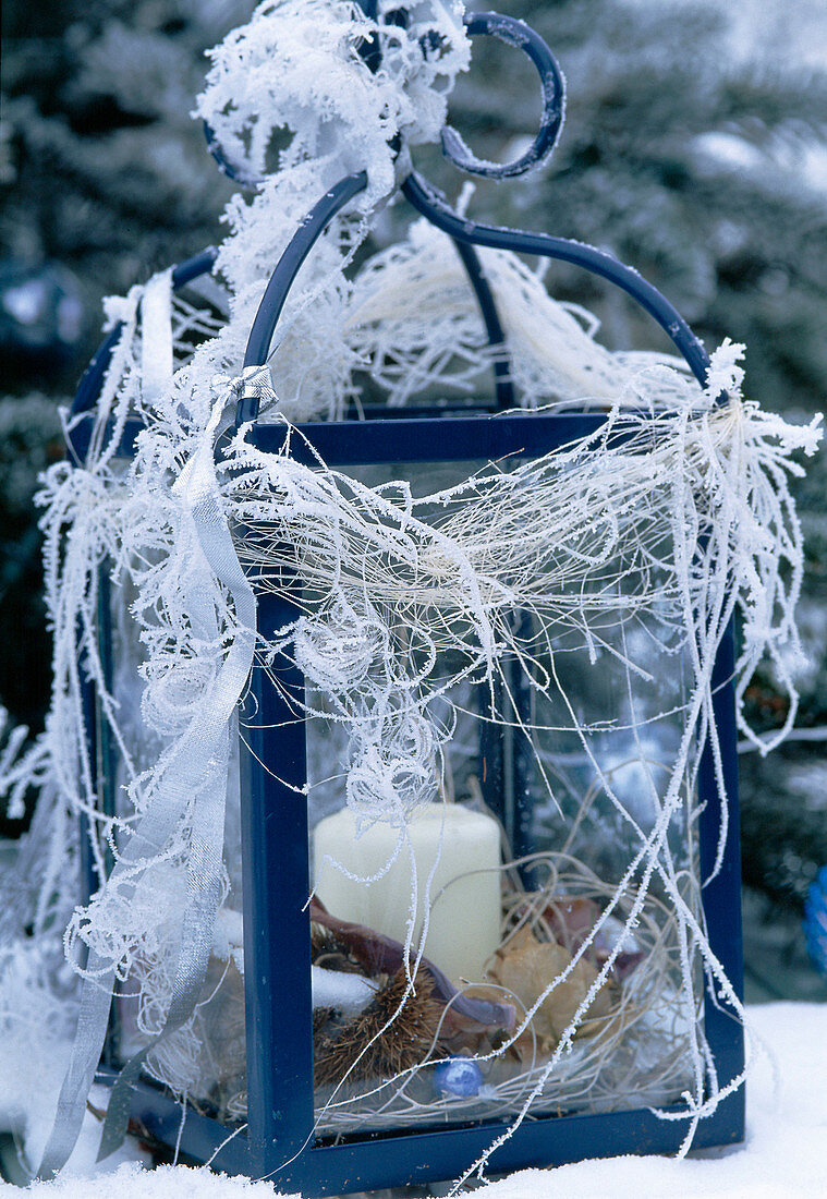 Decorated lantern with candle in hoarfrost