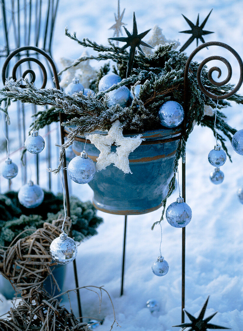 Iron rack with pot, twigs, tree balls and metal stars in hoarfrost