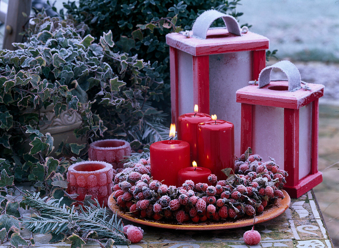 Table arrangement with pink (rose hip wreath, candles and lanterns, Hedera)