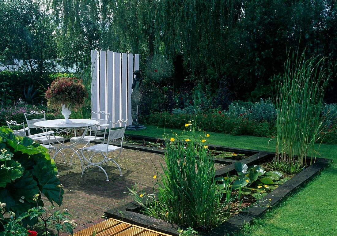 Paved terrace with white seating surrounded by rectangular water basins