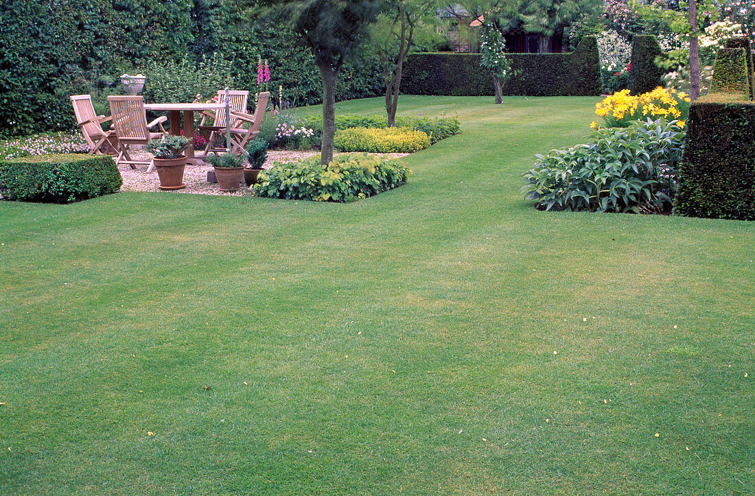 Gravel terrace with wooden seating area, pots with tub plants, beds with perennials