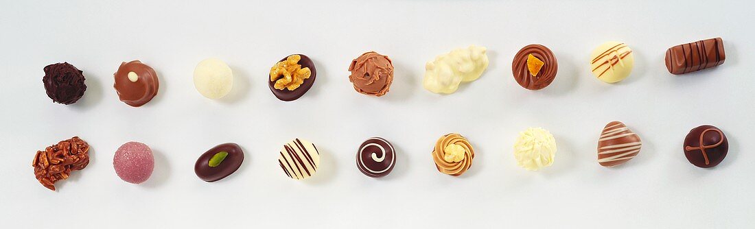 Assorted candies in rows on white paper