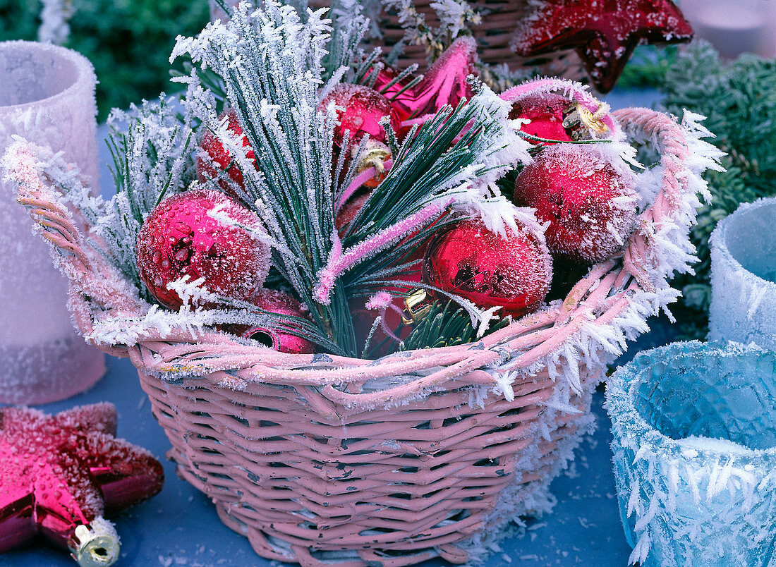 Willow basket with tree ornaments in pink and red with hoarfrost