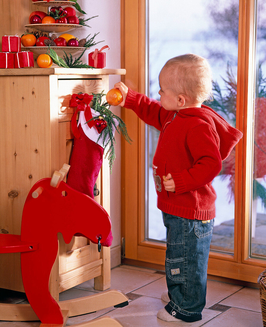 Little boy takes tangerine from Santa stocking