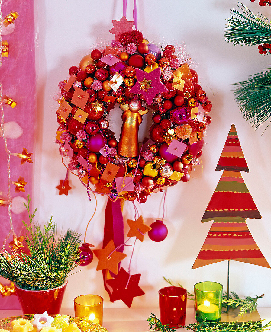 Hanging wreath made of baubles and Christmas tree decorations and angel in the middle