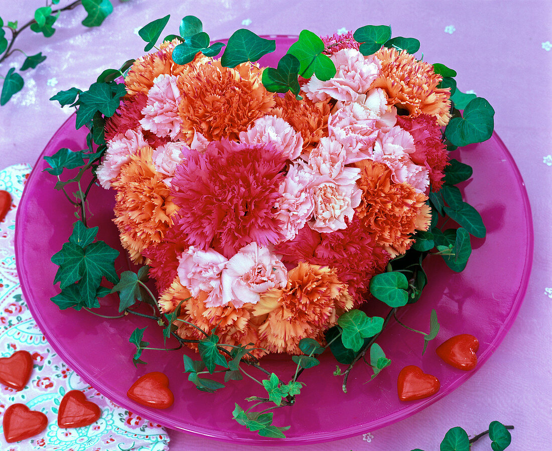 Blüten von Dianthus (Nelken) in Herz aus Oasis auf Glasteller