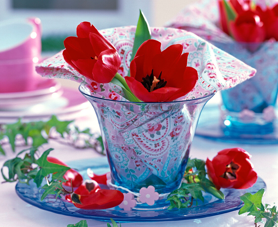 Tulipa (tulips, red) in small blue vase, patterned napkin