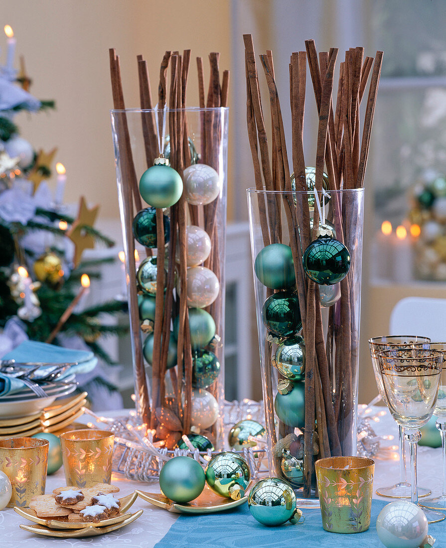 Cinnamon sticks in tall glasses with green and cream colored balls