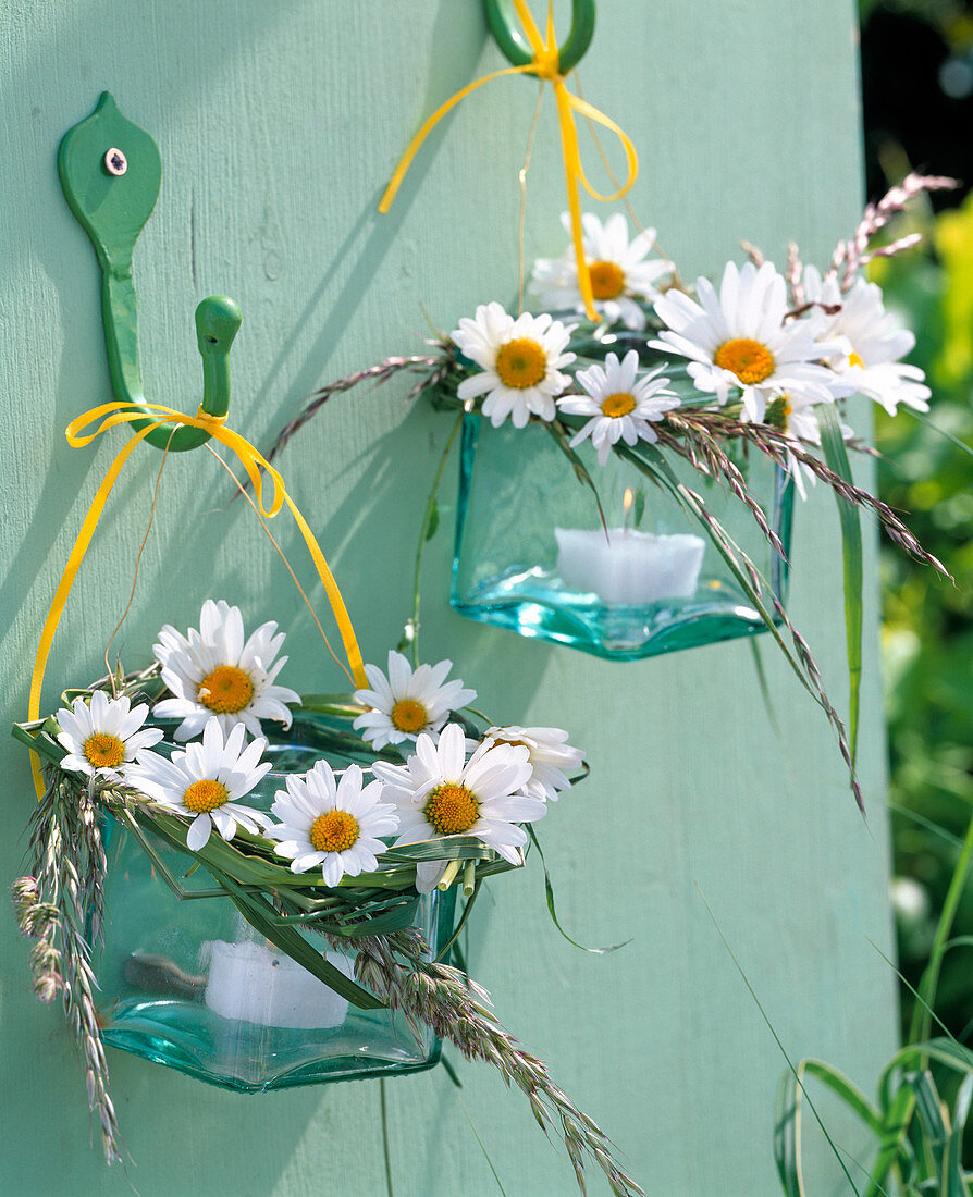 Windlichter mit Kränzchen aus Argyranthemum (Margeriten) und Gräsern