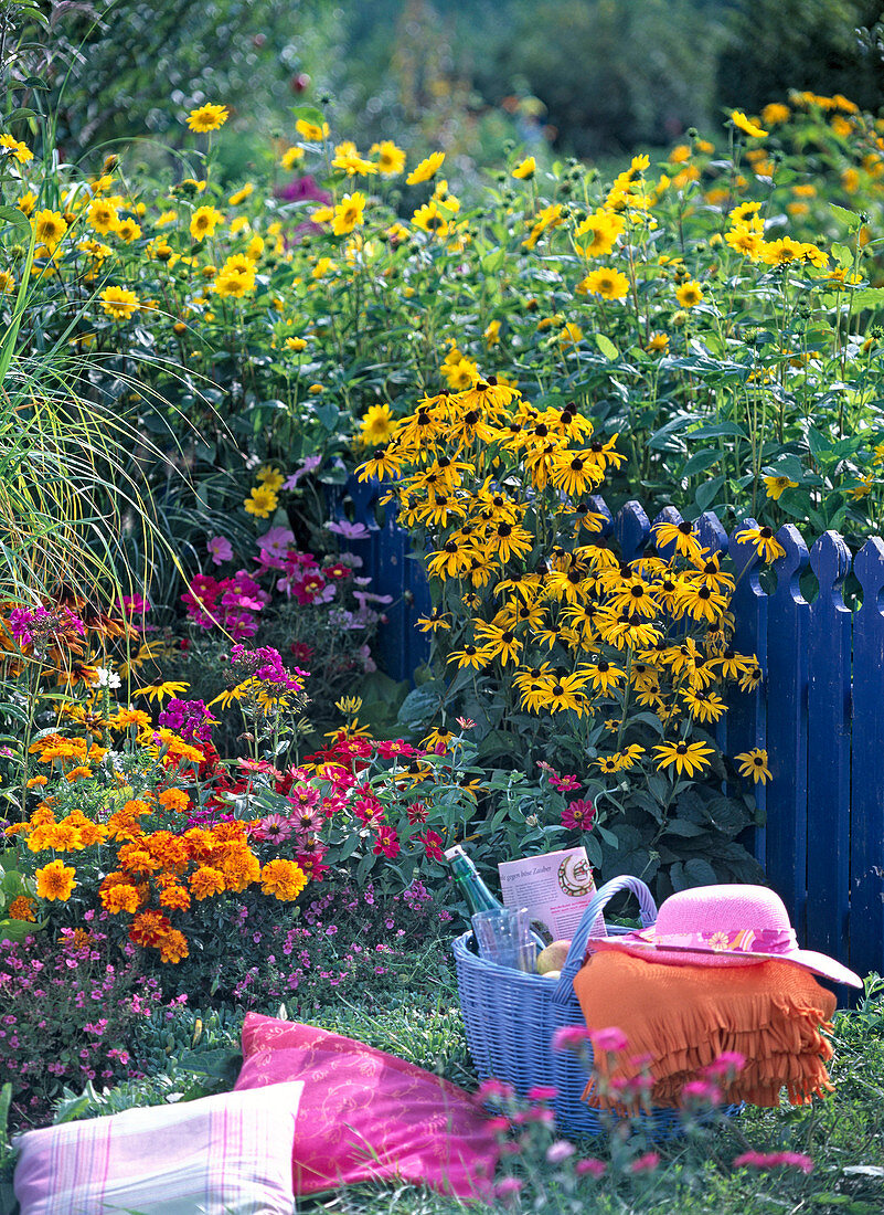 Picnic place at the flower bed with cushion and basket