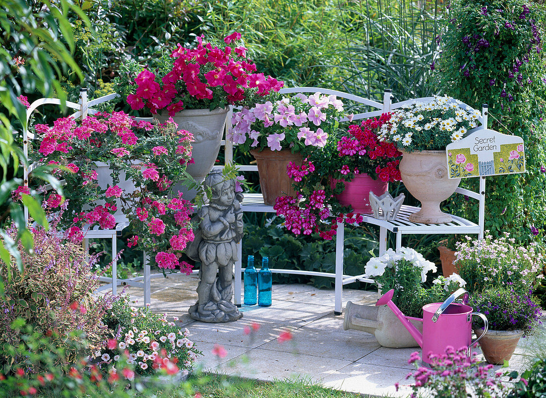 Semicircular white bench with pink and white flowering plants