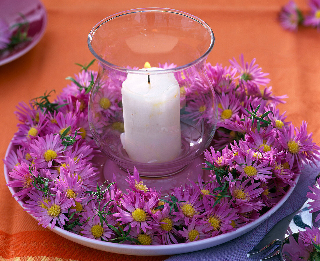 Kranz aus Aster (Astern) um Windlicht mit weißer Kerze