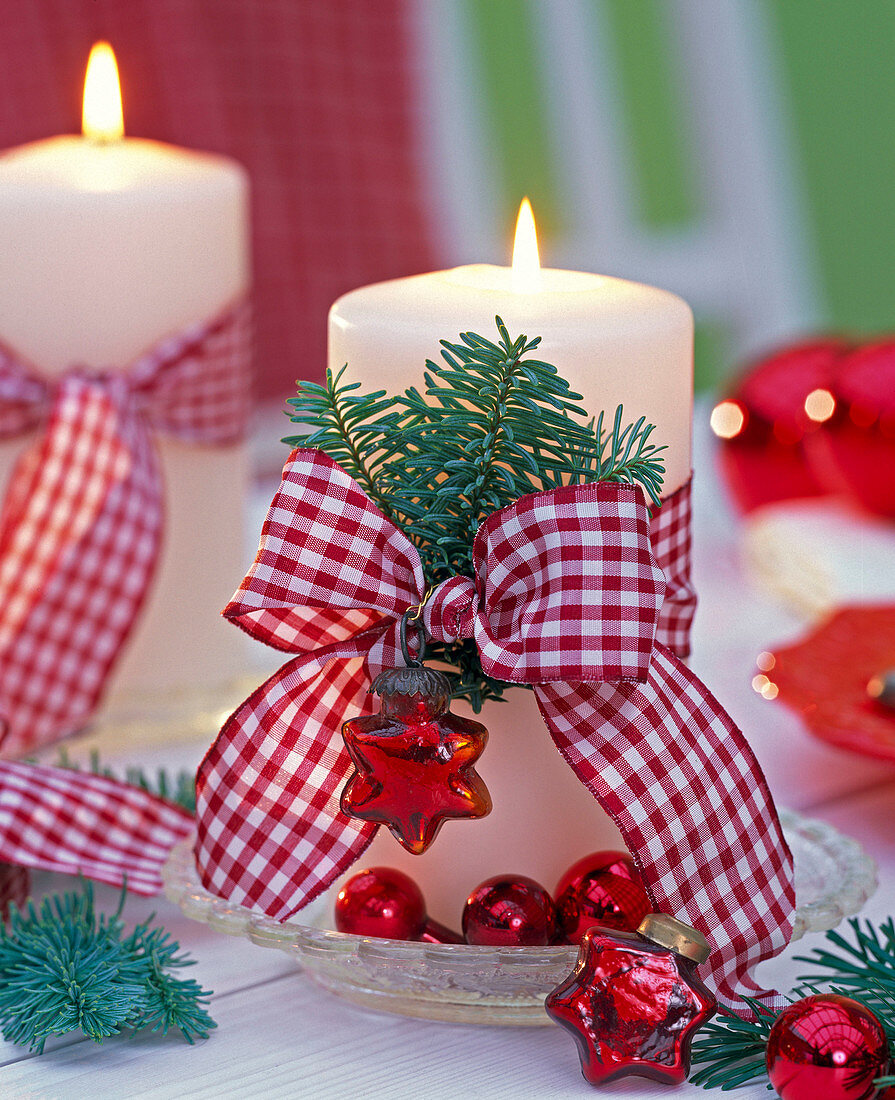 Abies branches with red and white checkered ribbon on white candle