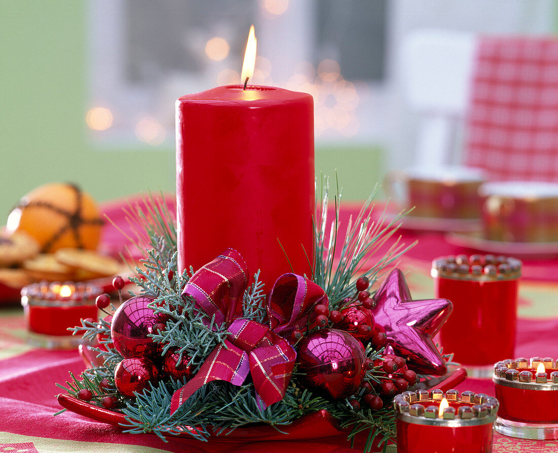 Red candle with twigs of Abies (fir), Chamaecyparis (false cypress)