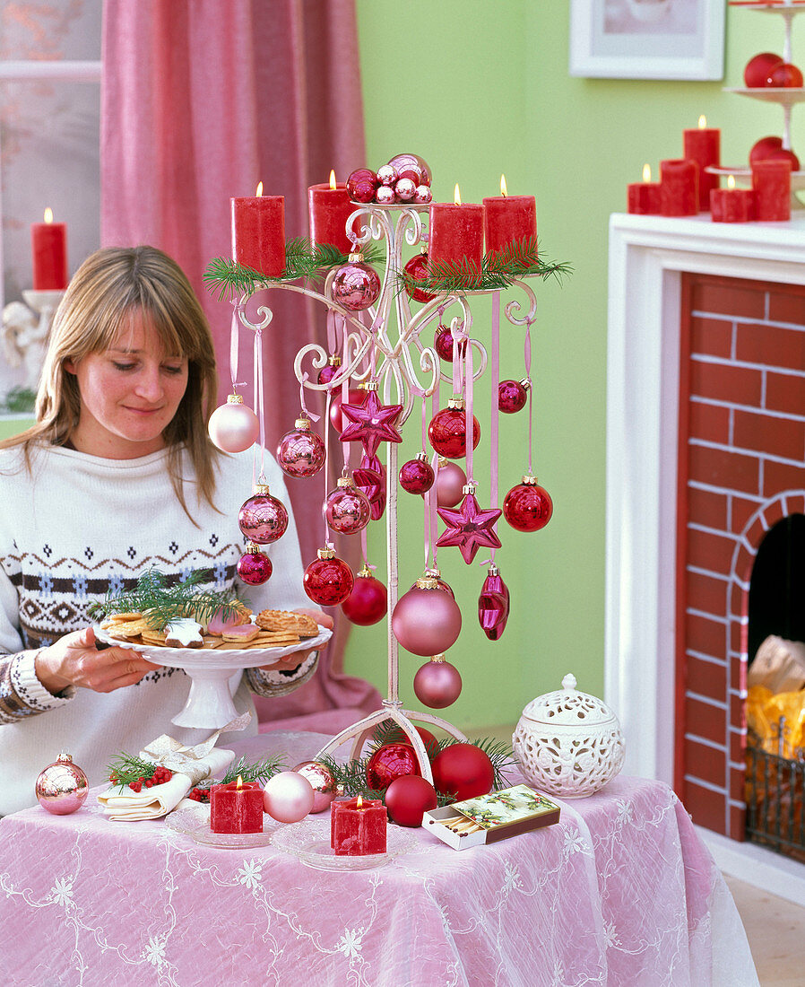 Frau mit Plätzchenschale sitzt am Tisch mit weihnachtlicher Dekoration