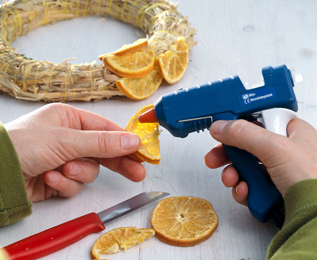 Gluing orange pieces to straw wreath