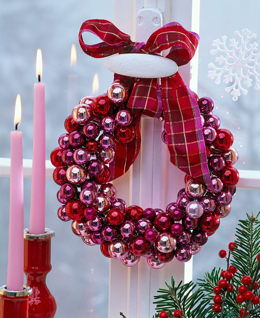 Wreath of small red, pink and purple Christmas tree balls on window handle