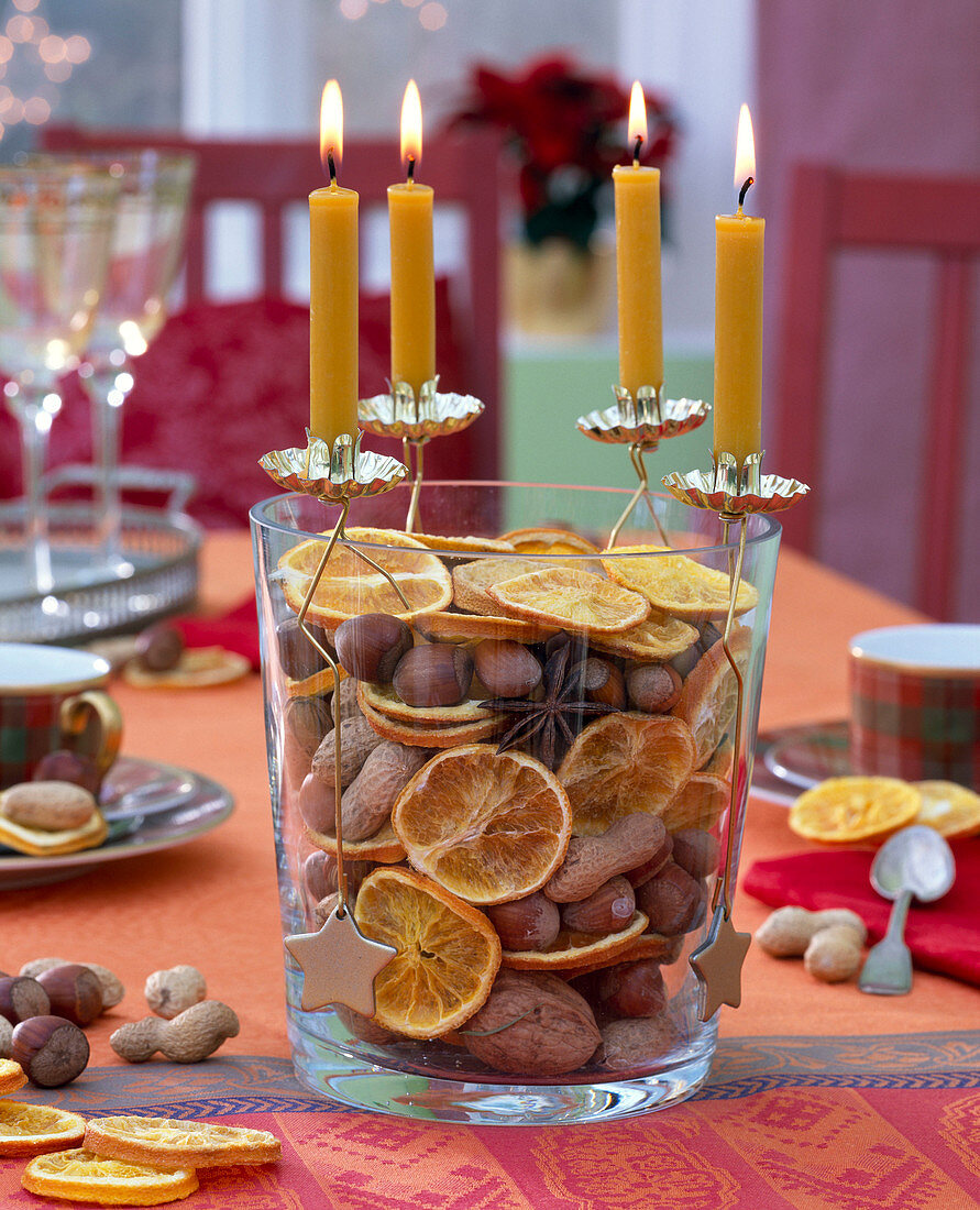 Advent wreath with yellow candles on vase filled with dried orange slices