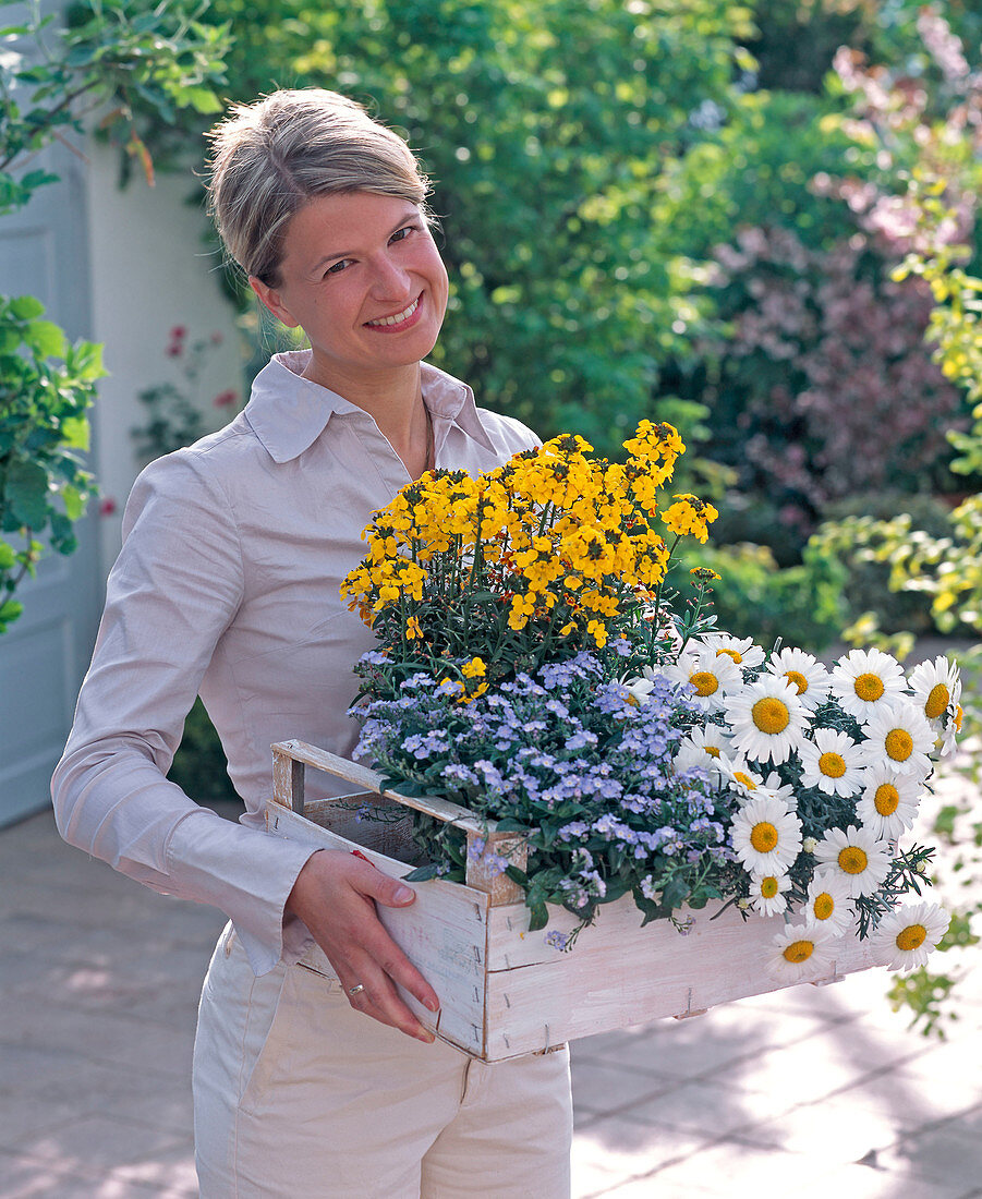 Young woman with myosotis (forget-me-not), Erysimum 'Gold'