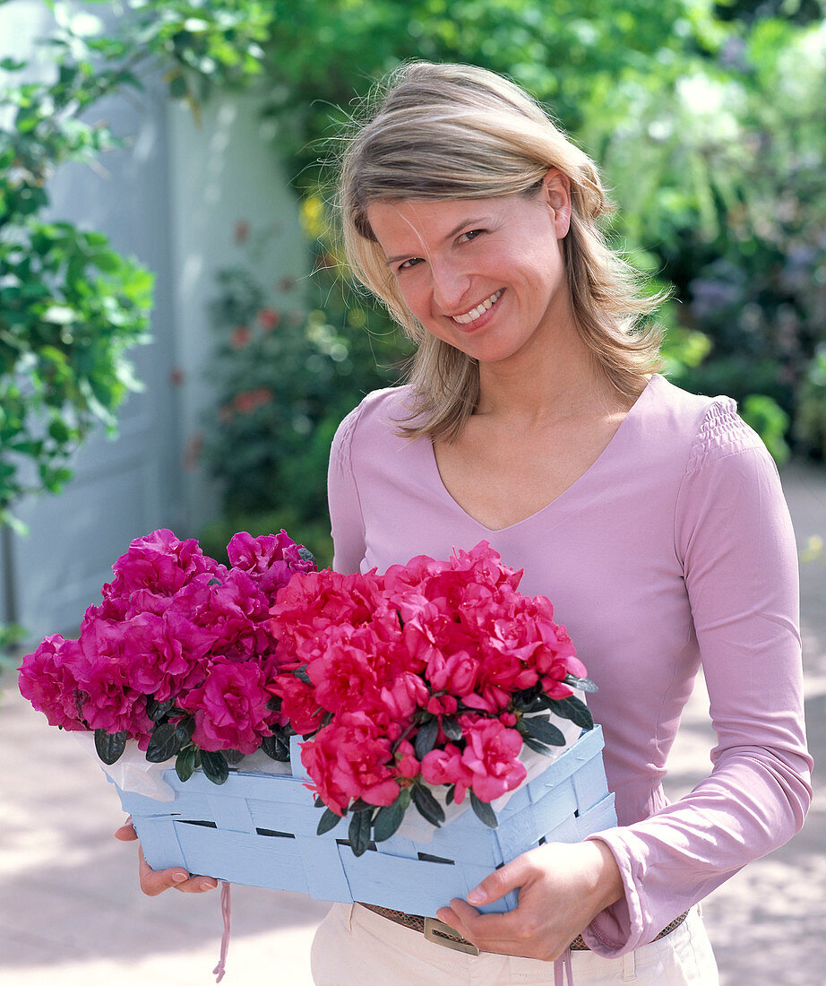 Junge Frau mit Rhododendron simsii (Zimmerazaleen)