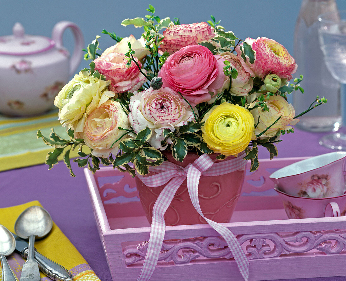 Strauß aus Ranunculus (Ranunkeln), Pittosporum (Klebsame) in rosa Reliefvase