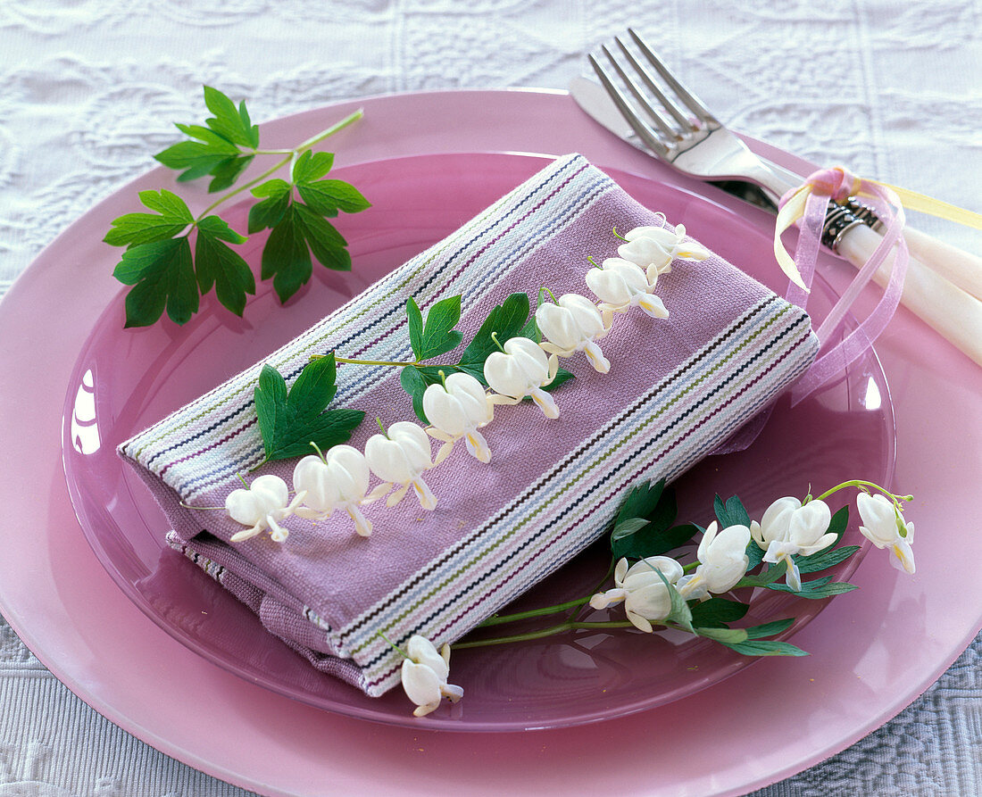 Dicentra (Tränendes Herz) auf gestreifter Serviette auf Glasteller