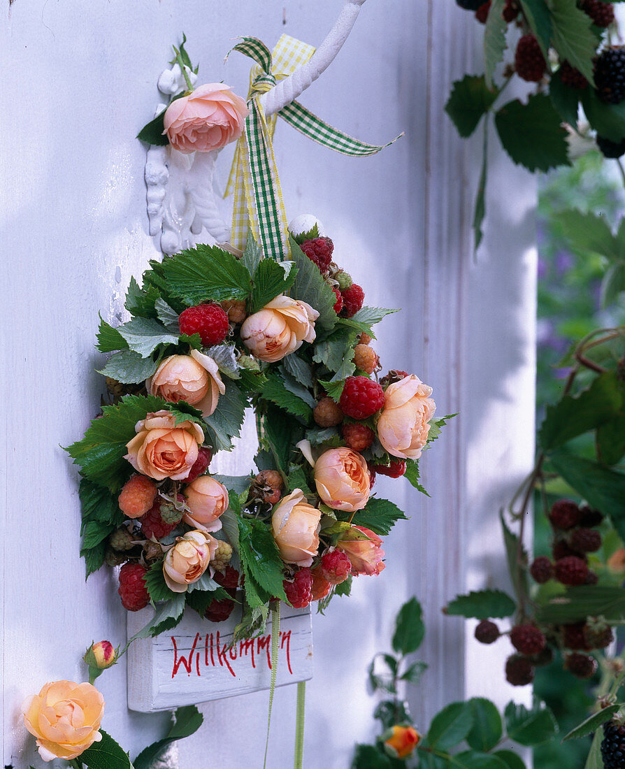 Wreath of pink (roses) and rubus (raspberries) with 'Welcome' sign